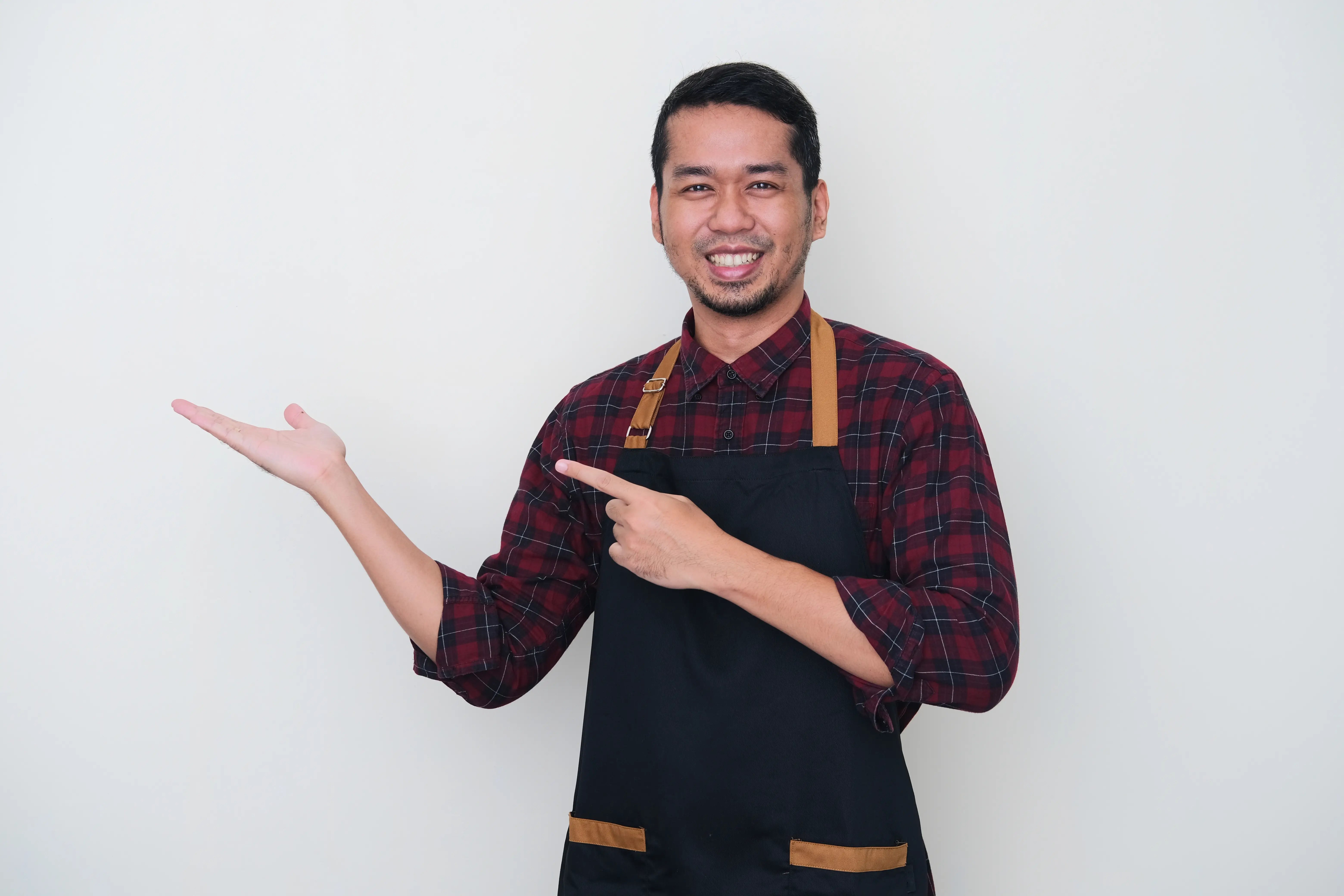 adult-asian-man-wearing-apron-pointing-right-side-happy-expression